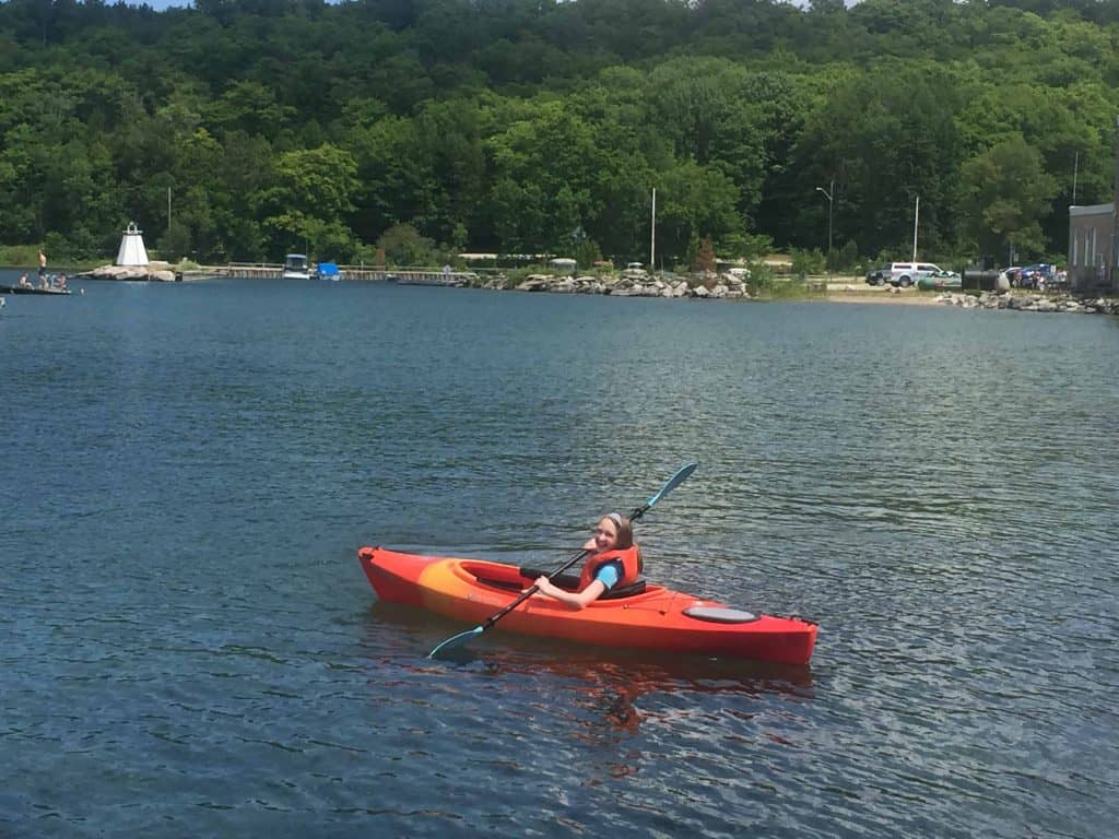 Young girl in red kayak holding paddle on lake huron in kagawong on manitoulin island.