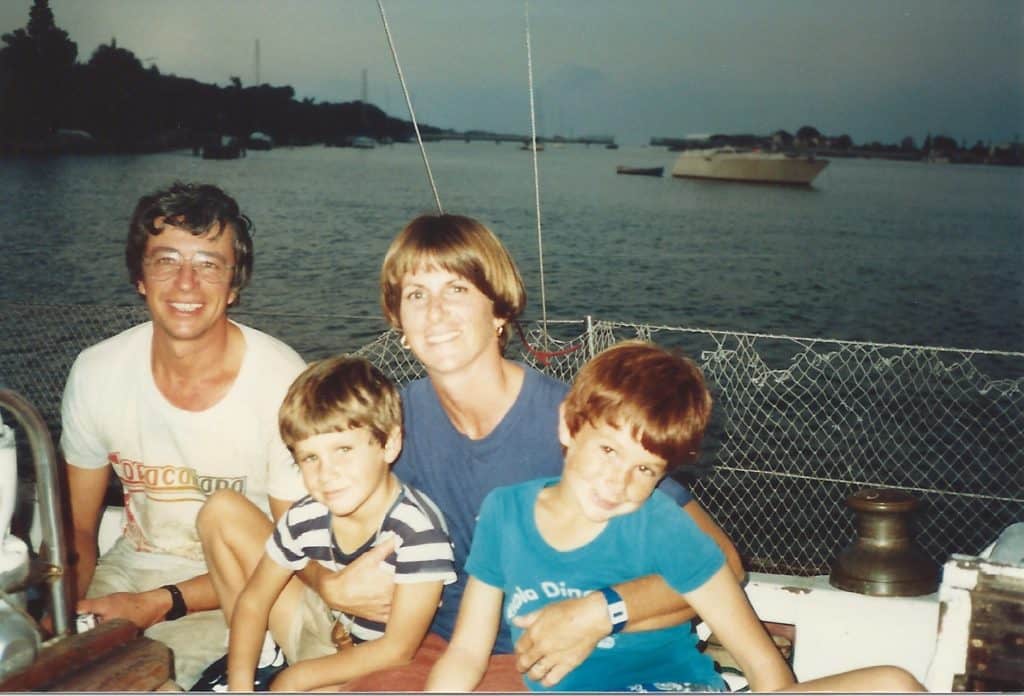 Couvreux family photo - man, woman and two boys sitting on boat.