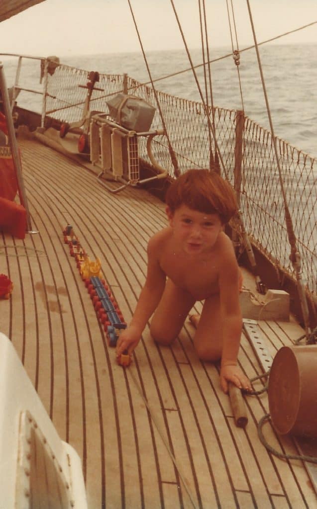 young boy playing on deck of sailboat