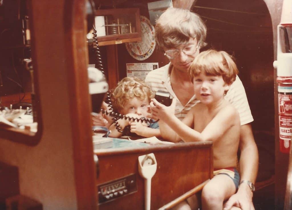 man and two boys in sailboat cabin