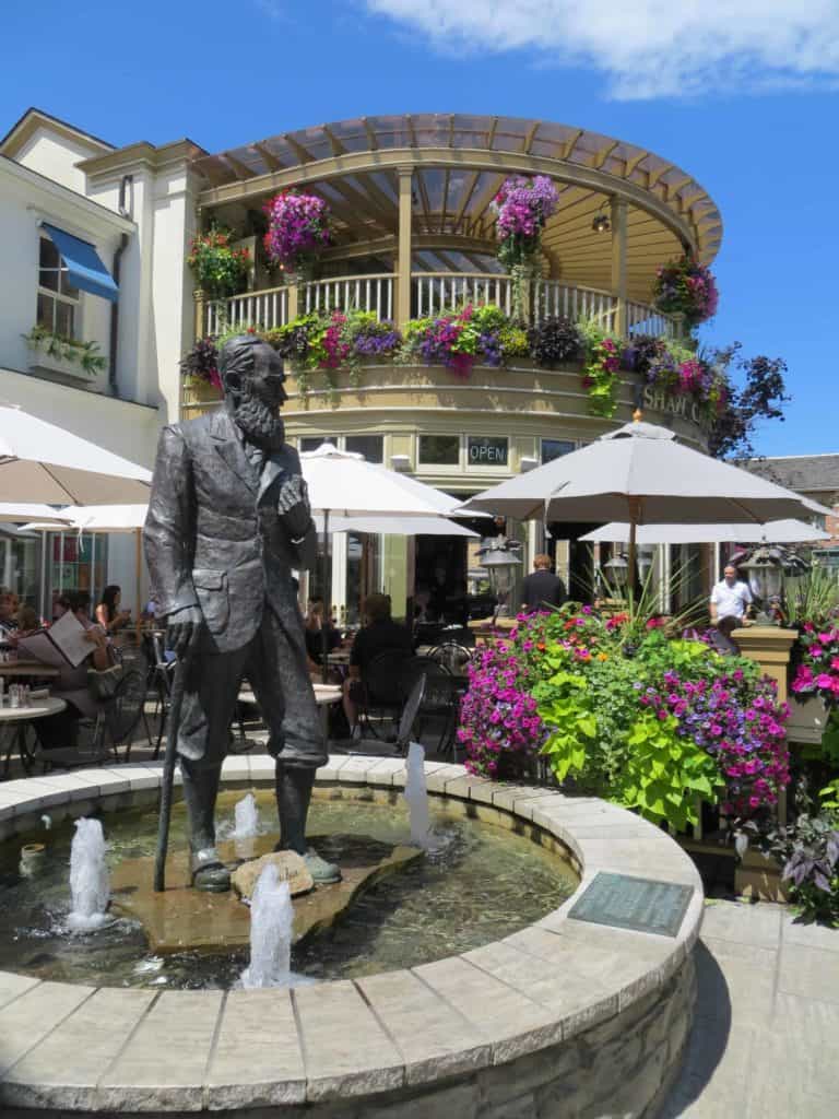 Fountain with statue of George Bernard Show surrounded by flowers outside the Shaw Cafe in Niagara-on-the-Lake.