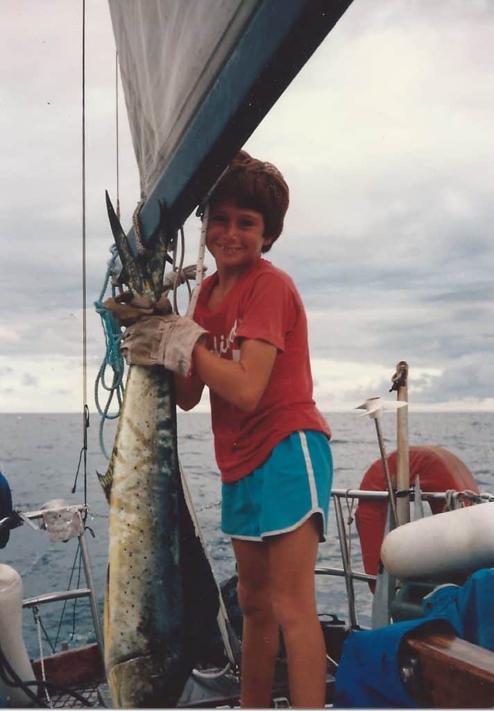 boy on sailboat holding large fish
