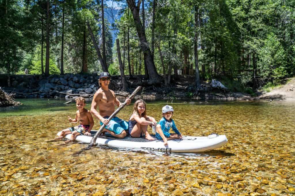 Paddling with the family in Yosemite Valley - man holding paddle and three children on a paddle board.