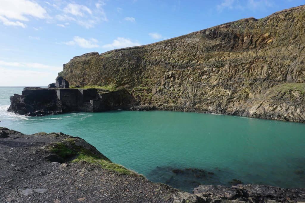Blue/green water in Blue Lagoon surrounded by rocky cliffs in Pembrokeshire.