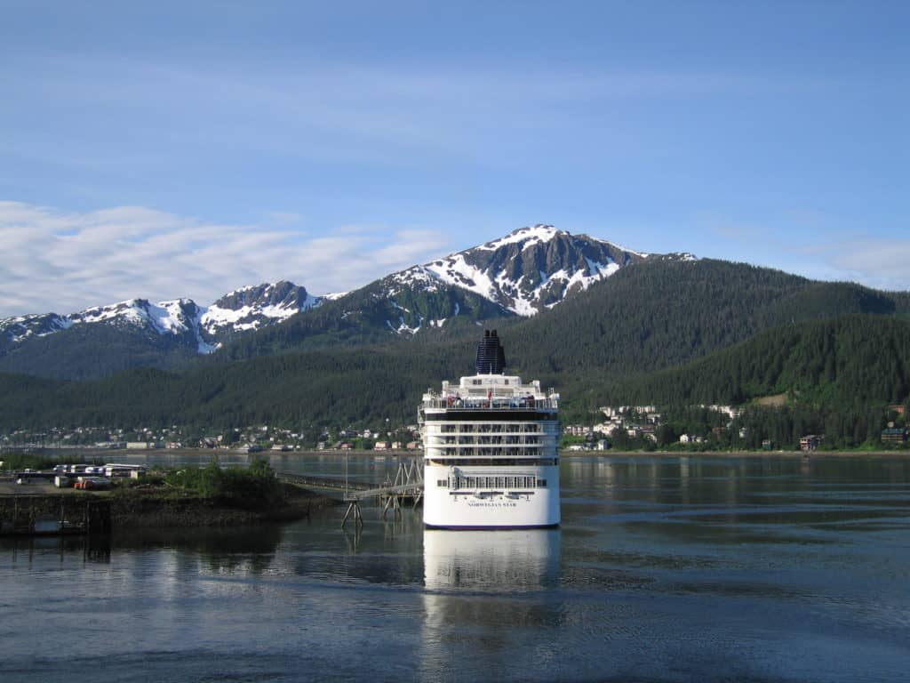 Cruise ship anchored in Juneau with snow-topped mountains in background.