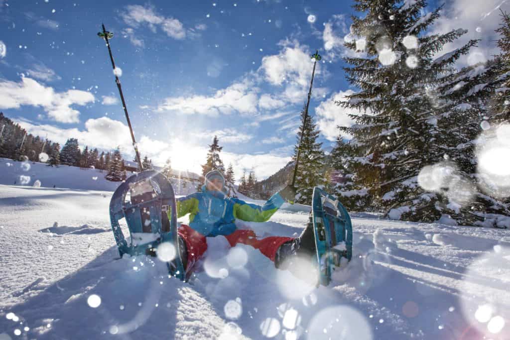 woman with snowshoes sitting in snow