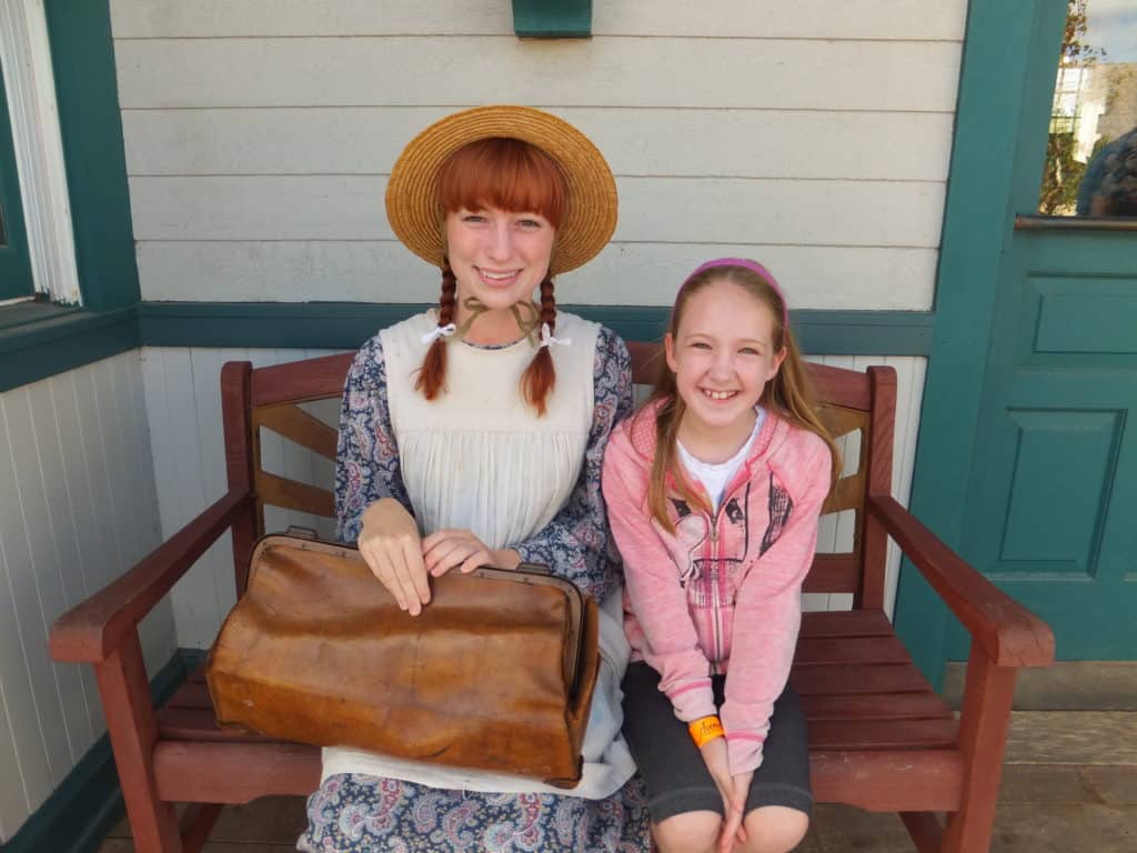 young girl sitting on bench with anne of green gables in prince edward island