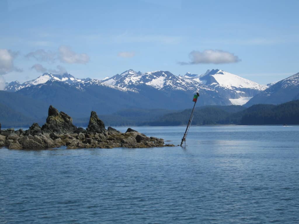 juneau-alaska-bald eagle atop post in water-mountains in background