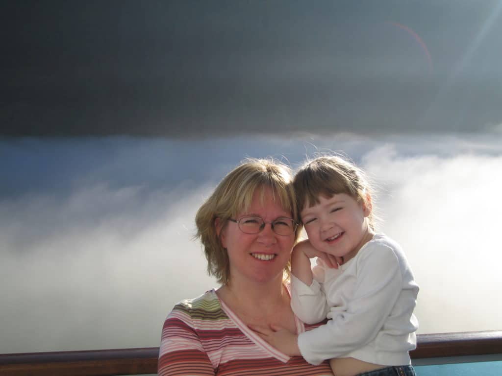 Mom and daughter on cruise ship balcony on misty morning in Juneau, Alaska.