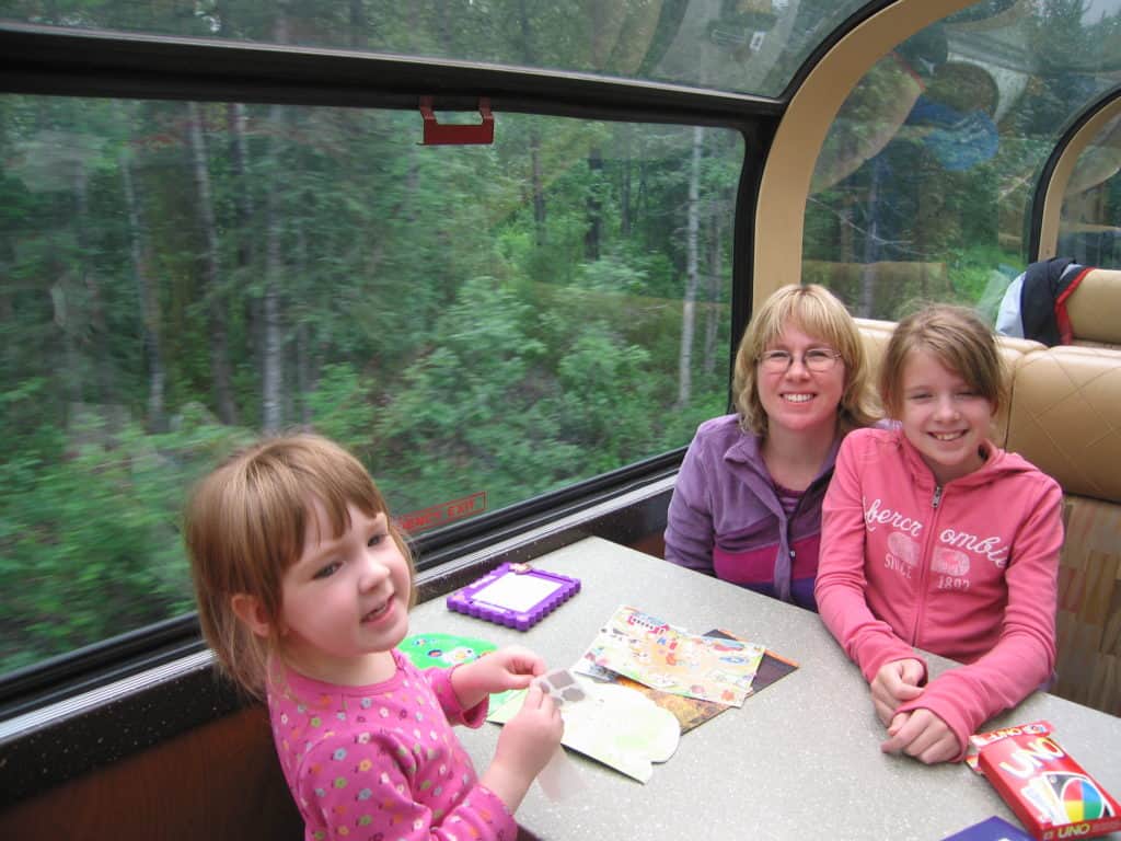 woman and two girls sitting at table in railroad car in alaska