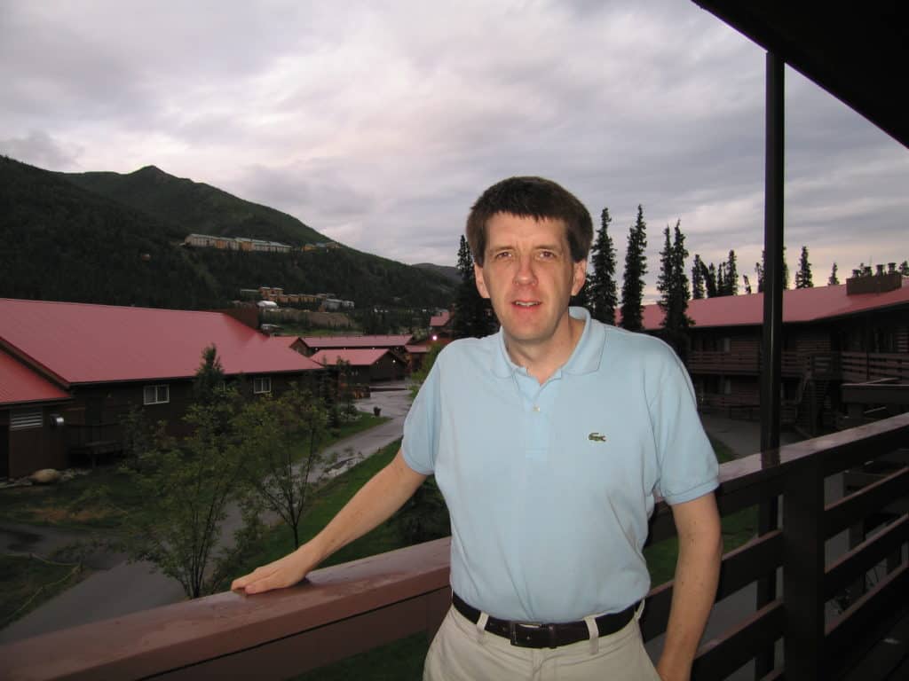 Man standing outside hotel room at 11pm in Alaska when it's still daylight.