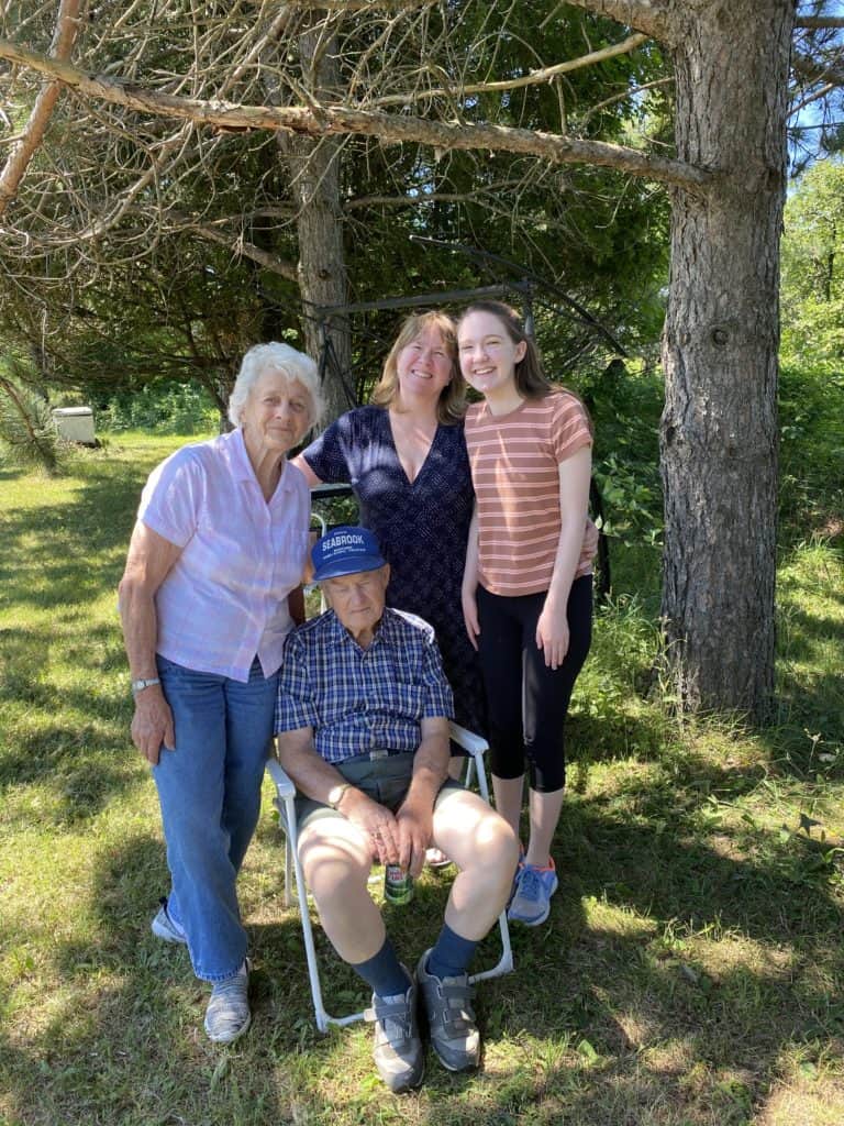 woman with elderly parents and teen daughter sitting outside.