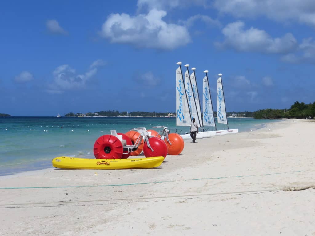 man walking on beach by watersports equipment beaches negril, jamaica.