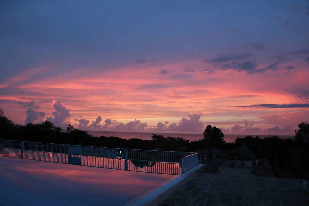 Pink sunset by pool at Memories Holguin Beach Resort in Mexico.