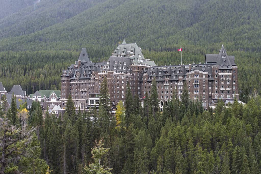 Banff Springs Hotel from a distance surrounded by evergreen trees.