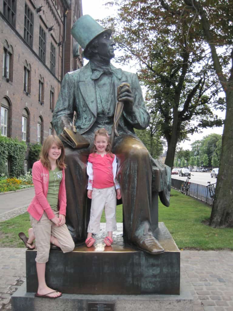 Teen girl and younger girl standing with statue of Hans Christian Andersen near Radhuset in Copenhagen.