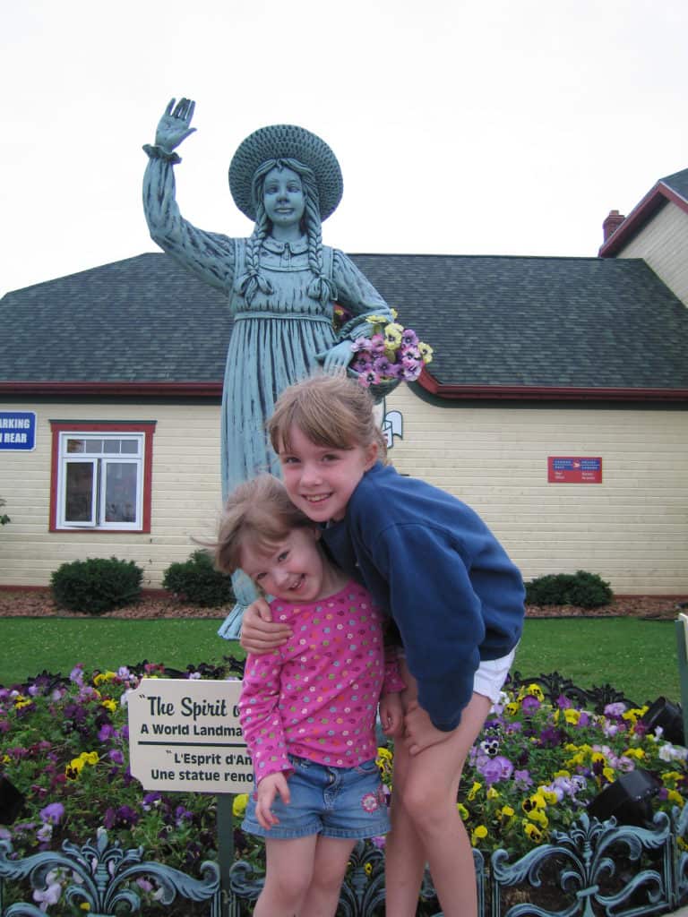 Two young girls with Spirit of Anne statue at Gateway Village, Prince Edward Island, Canada.