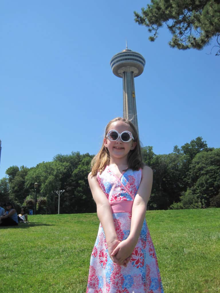 Young girl in flowered dress in front of Skylon Tower, Niagara Falls.