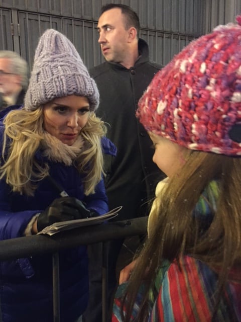 Young girl in pink winter hat meeting Kristin Chenowith outside Broadway theatre.