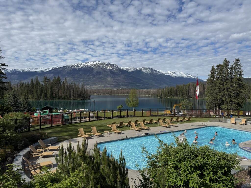 outdoor pool at Jasper Park Lodge with snow-capped mountains in background.