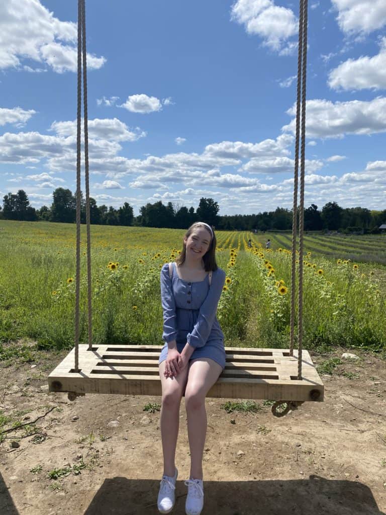 Young woman on swing with sunflowers in background at Terre Bleu Lavender Farm.