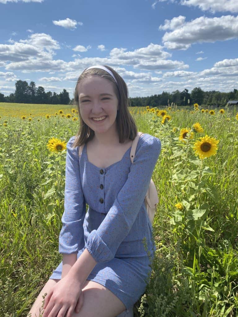 Young woman sitting in field of sunflowers at Terre Bleu Lavender Farm.