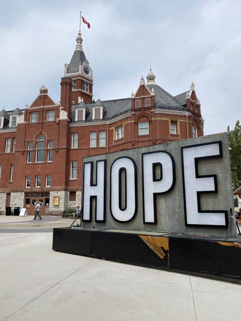 Stratford City Hall with large sign on grey background with white block letters outlined in black reading HOPE>