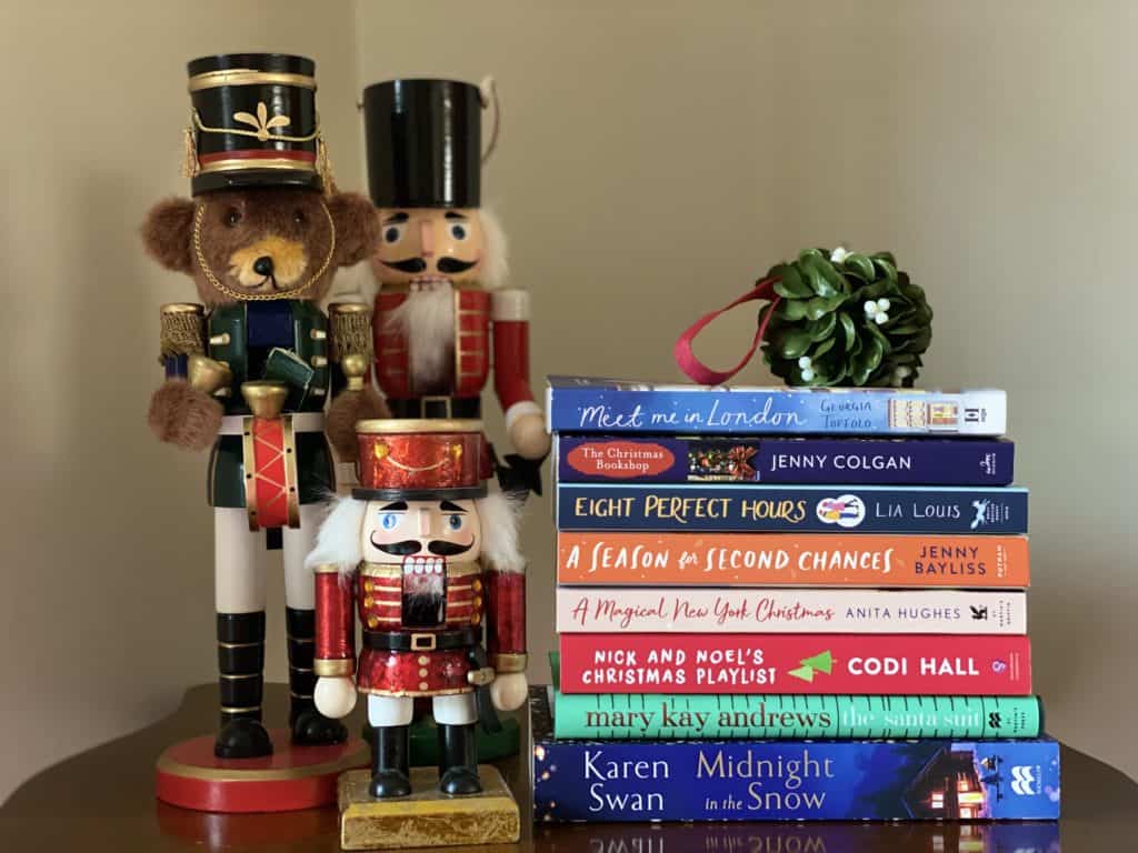 Stack of 2021 Christmas books with mistletoe on top beside three nutcrackers.