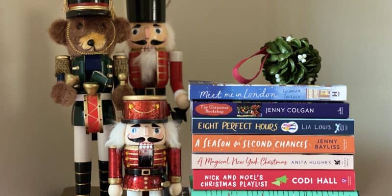 Stack of 2021 Christmas books with mistletoe on top beside three nutcrackers.