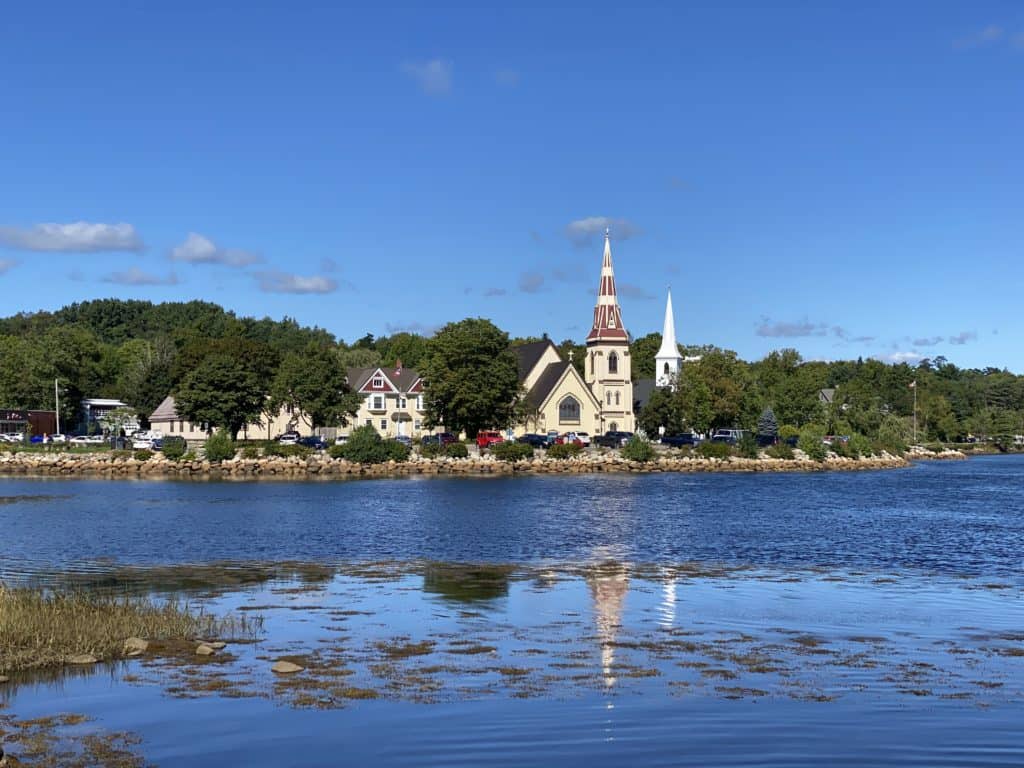 Mahone Bay, Nova Scotia church along waterfront with partial reflection in the water.