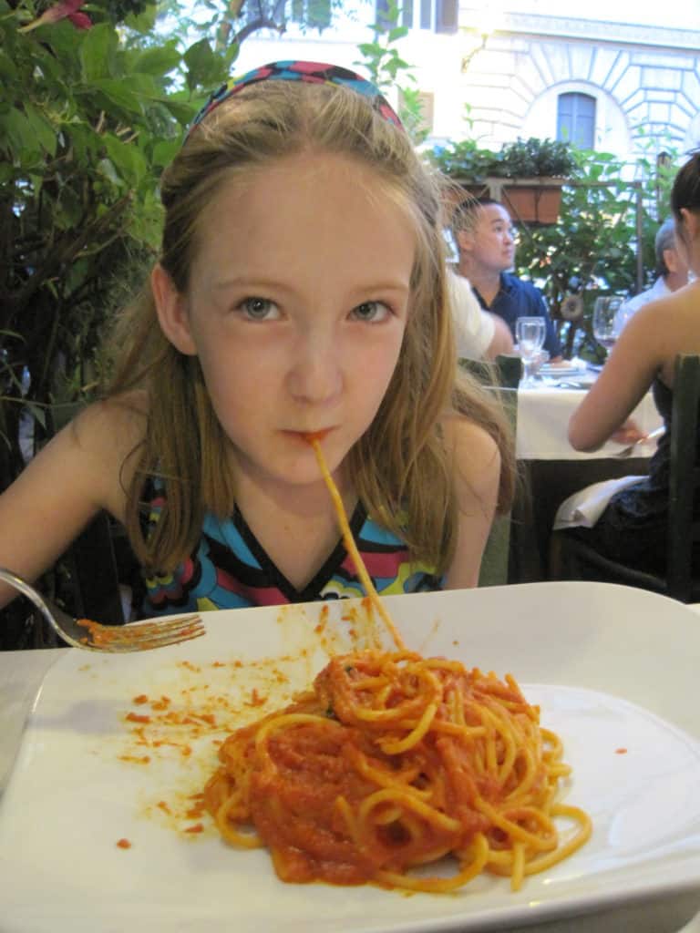 Young girl eating a plate of spaghetti in Rome, Italy.