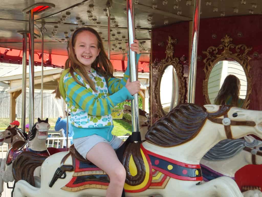 Young girl seated on a horse on the carousel at Sandspit Amusement Park in Cavendish, Prince Edward Island.