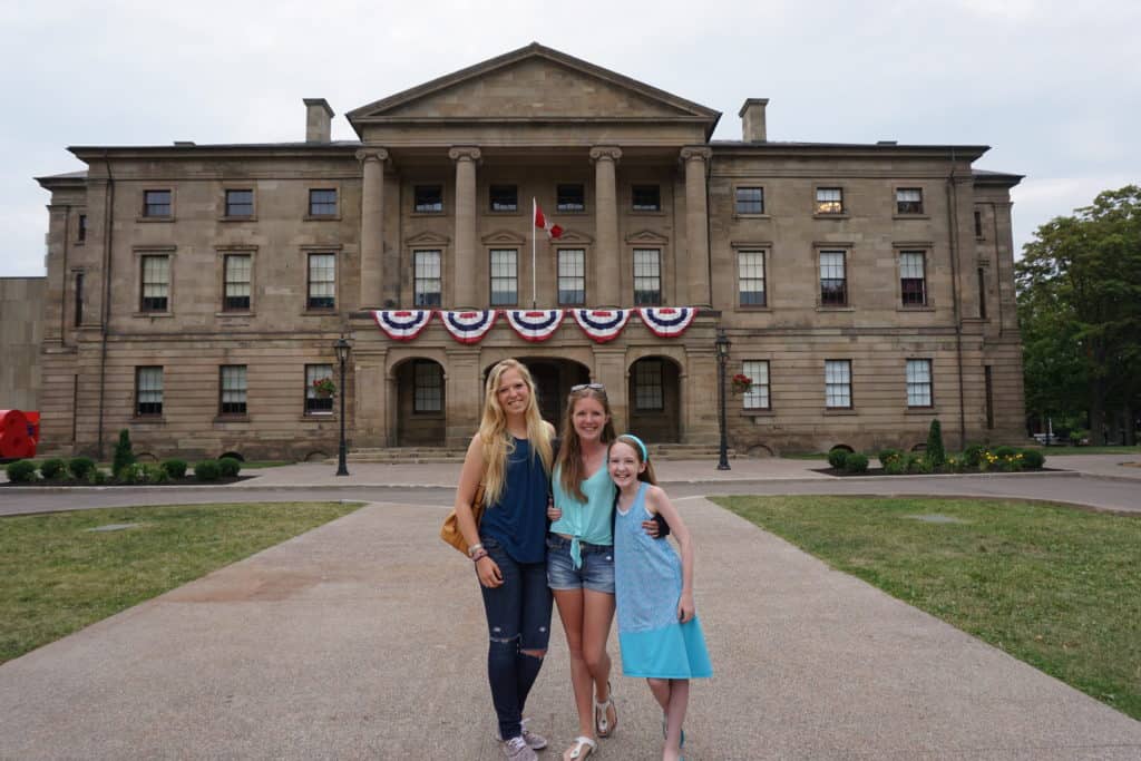 Two teens and younger girl posing outside Province House in Charlottetown.