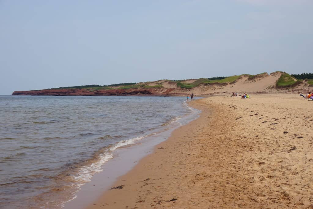 Cavendish Beach in Prince Edward Island National Park with sand dunes and people in the distance.