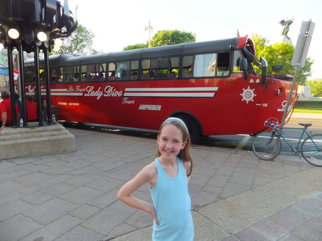 Young girl posing in front of red Lady Dive amphibus in Ottawa, Canada.
