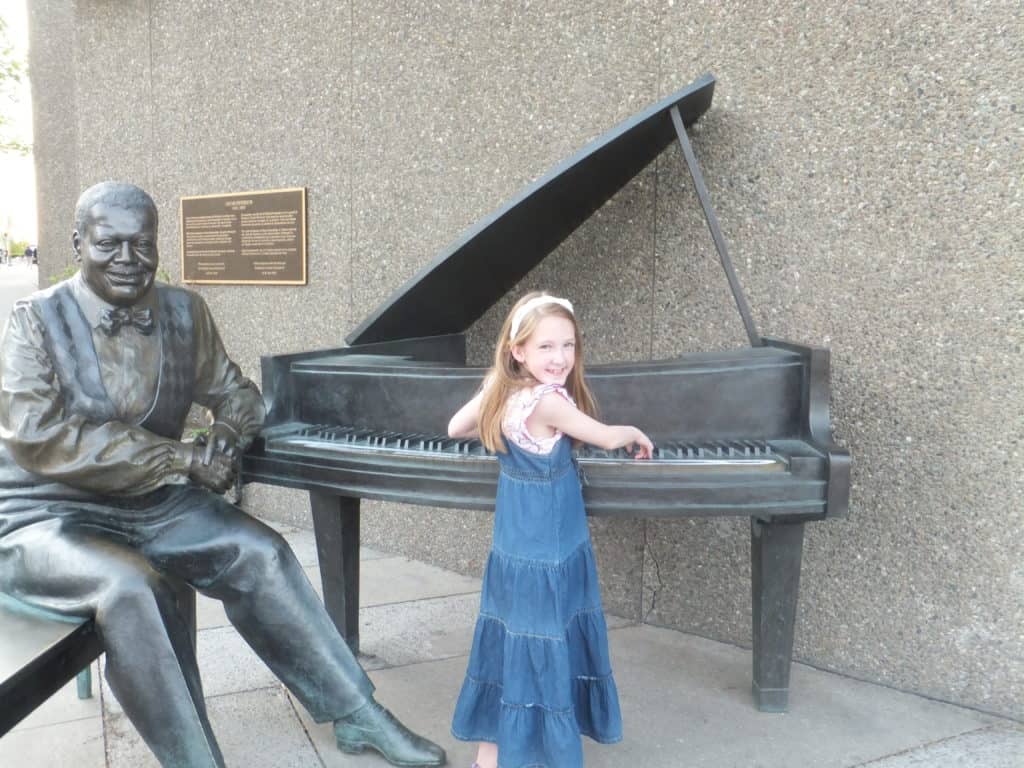 Young girl with Oscar Peterson sculpture outside National Arts Centre in Ottawa.