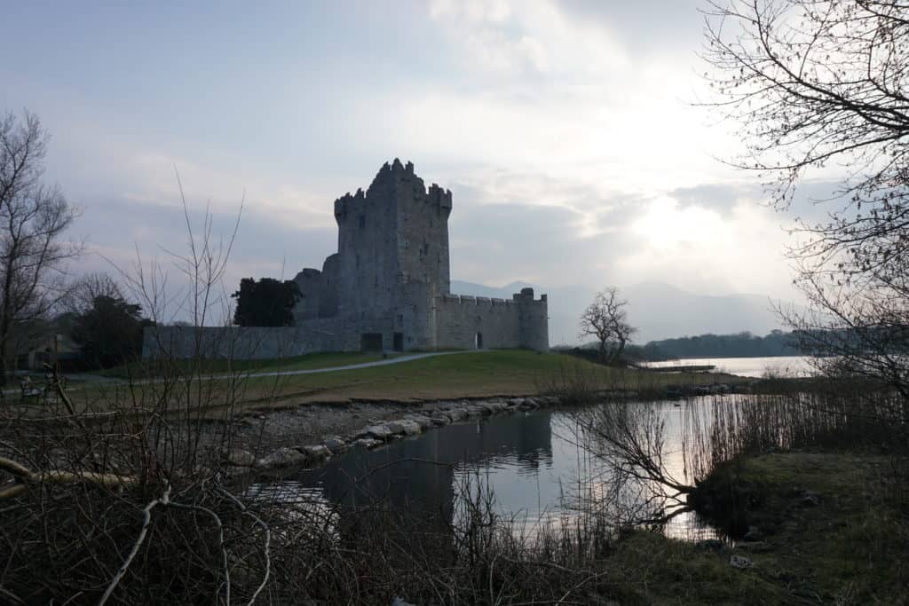 Stone castle alongside water as the sun is setting - Ross Castle in Killarney, Ireland.