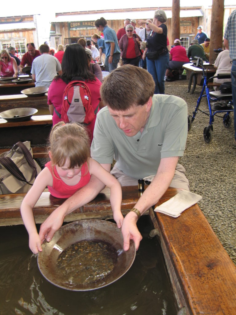 Young girl and her dad panning for gold at an attraction near Fairbanks, Alaska.