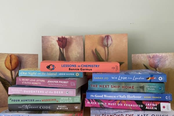 stack of books in front of prints of tulips