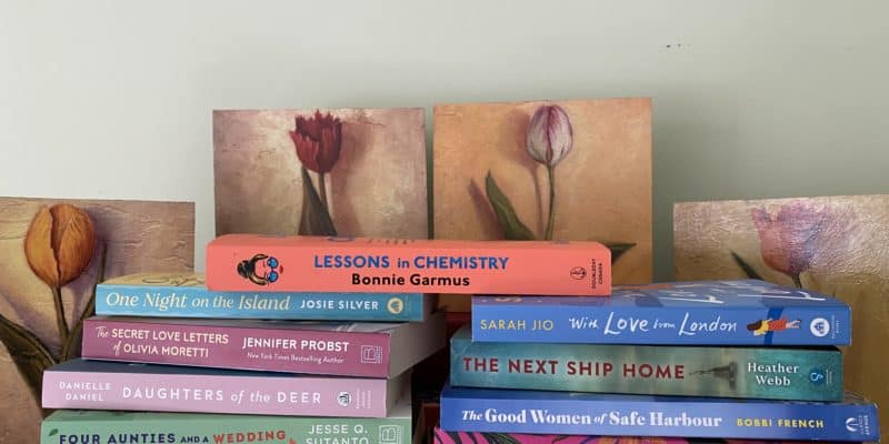 stack of books in front of prints of tulips