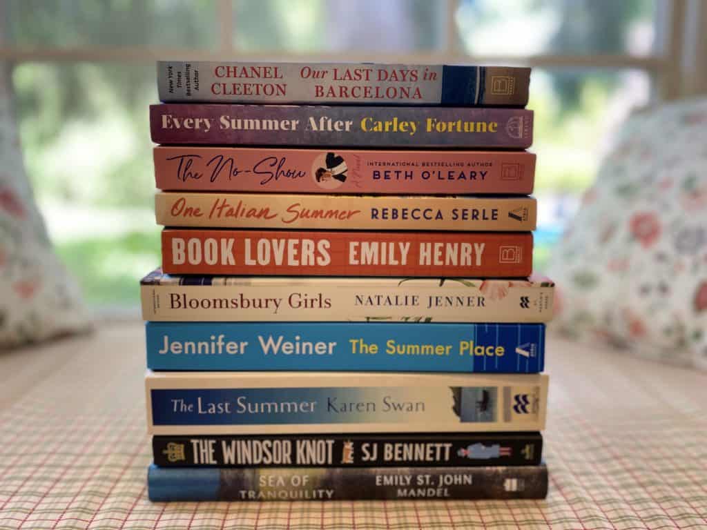 Stack of books in front of window.