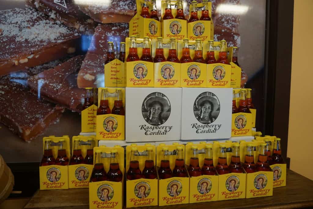 Display of bottles of raspberry cordial - stacked yellow cartons with image of Anne of Green Gables each holding four bottles with red liquid.