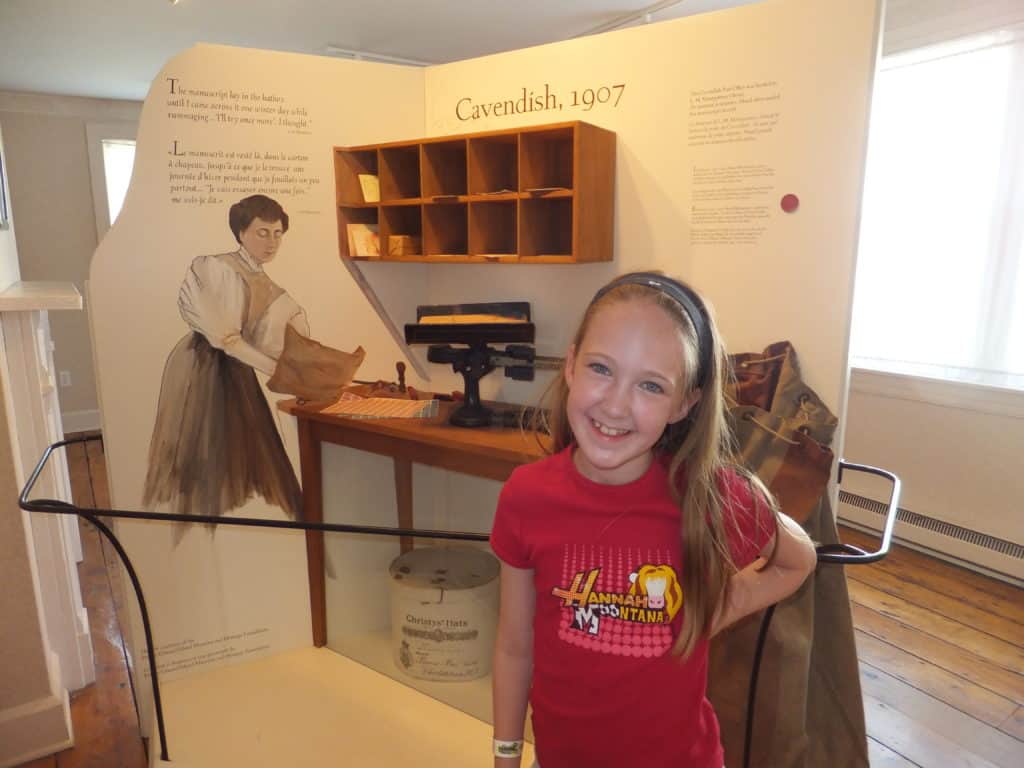 Young girl in red shirt in front of exhibit at Green Gables post office in Cavendish, PEI.