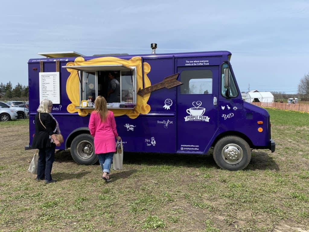 Two women standing in front of Purple Perk Coffee truck at Tasc Tulip Farm.