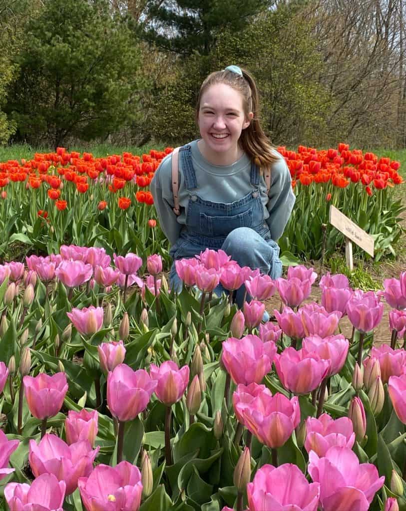 Young woman sitting among pink and red tulips at Tasc Tulip Farm.