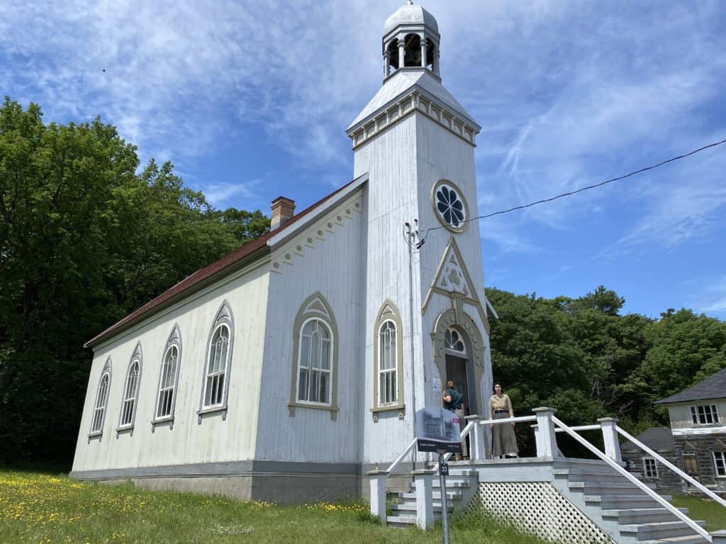 White wooden church on Grosse-Île with two women standing on outside door