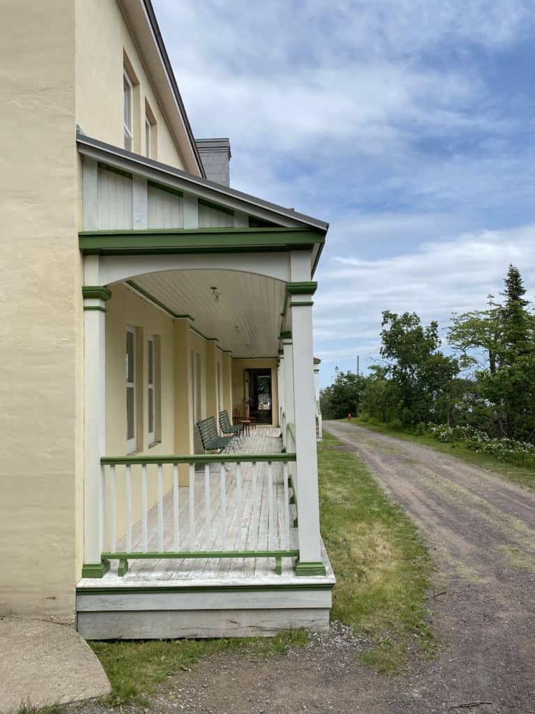 Exterior of hotel on Grosse-Île - painted yellow with green trim - porch with green benches