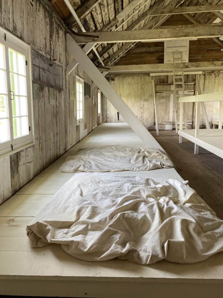 interior of old building on Grosse-Île with long wooden platforms for immigrants to share sleeping quarters - blanket on platform