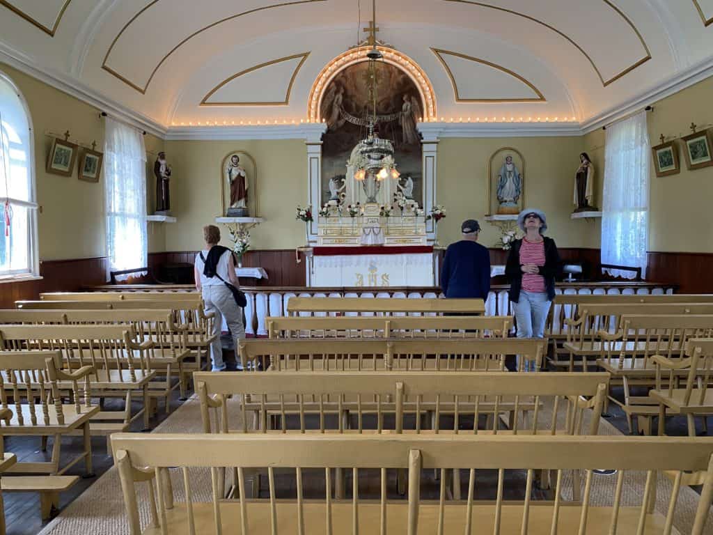 three people observing interior of church on Grosse-Île, Québec