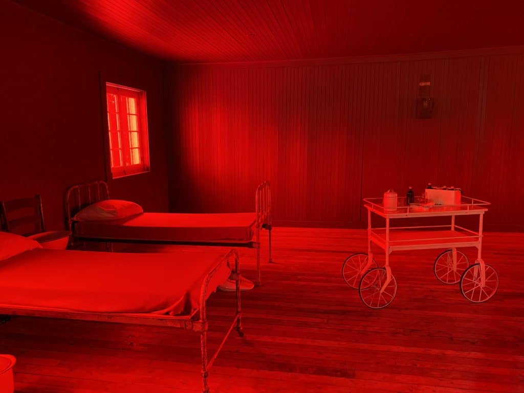 hospital room with two beds and cart bathed in red light